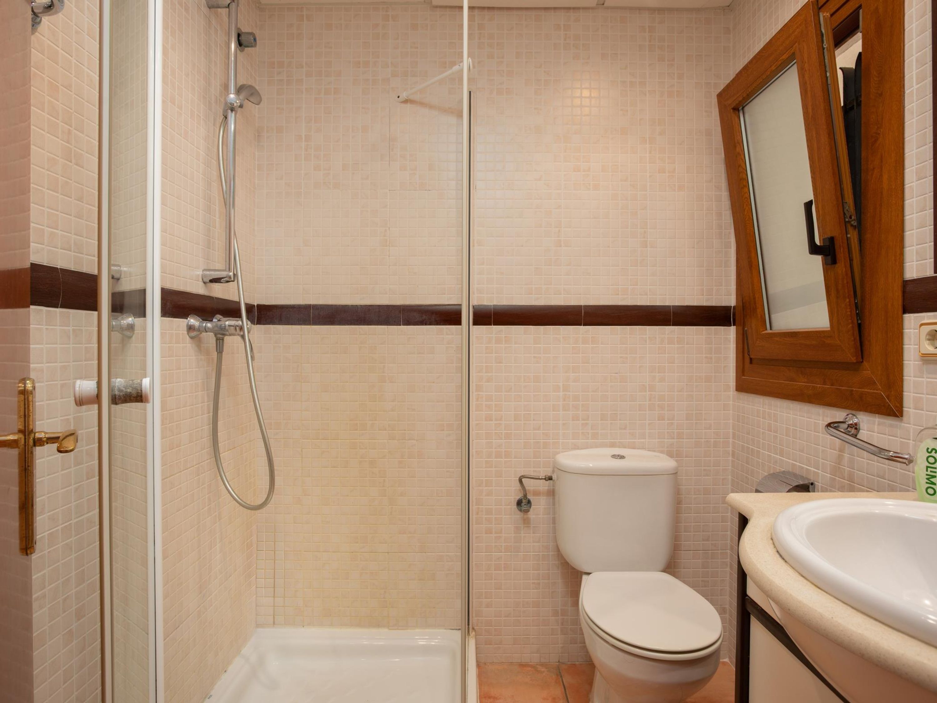 Un baño con ducha de vidrio, inodoro y lavamanos.