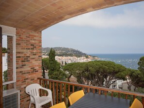 A balcony with a view of a coastal town, a table, and two chairs. - Apartament amb Espectaculars Vistes al Mediterrani (Palafrugell)