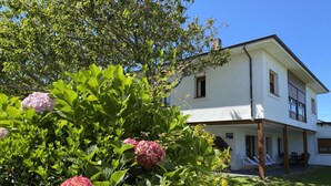 A two-story building with a white exterior, a covered porch, and a well-maintained garden with hydrangea flowers.