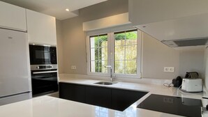 A modern kitchen with a large island, built-in oven, and a window providing natural light.