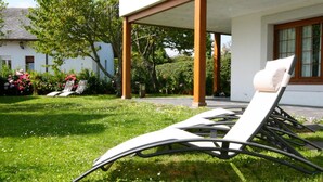 A sunlit outdoor seating area with lounge chairs and a pergola structure.