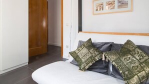 Une chambre à coucher avec un lit, deux oreillers, une porte en bois et un mur orné de tableaux.