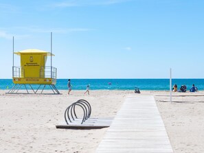 A lifeguard tower on a beach with a wooden walkway leading to it.