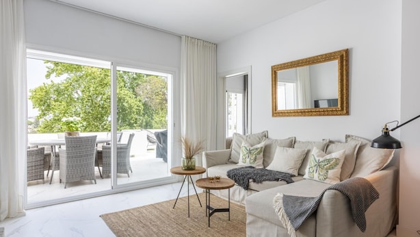 A modern living room with a sofa, a coffee table, and a large window.