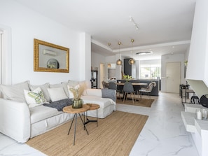 A modern living room with a sofa, coffee table, and dining area.