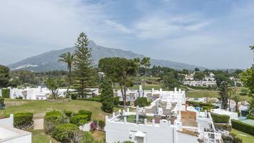 Un barrio residencial con casas blancas, céspedes verdes y una montaña al fondo.