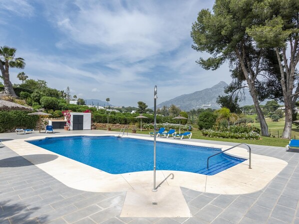 A swimming pool with a clear view of the surrounding landscape, including trees and distant mountains.