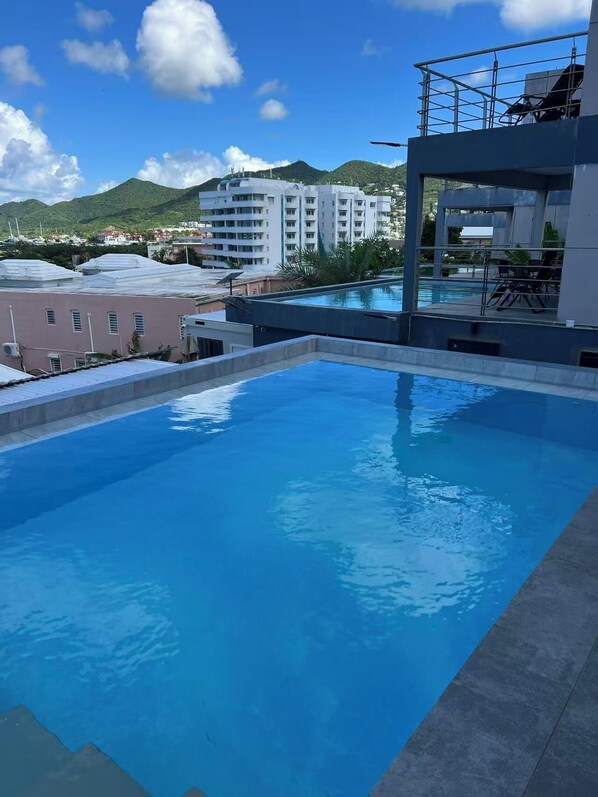 A rooftop swimming pool with a clear view of surrounding buildings and hills.