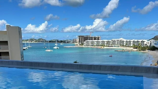 Una piscina con vista a una playa y un hotel al fondo.