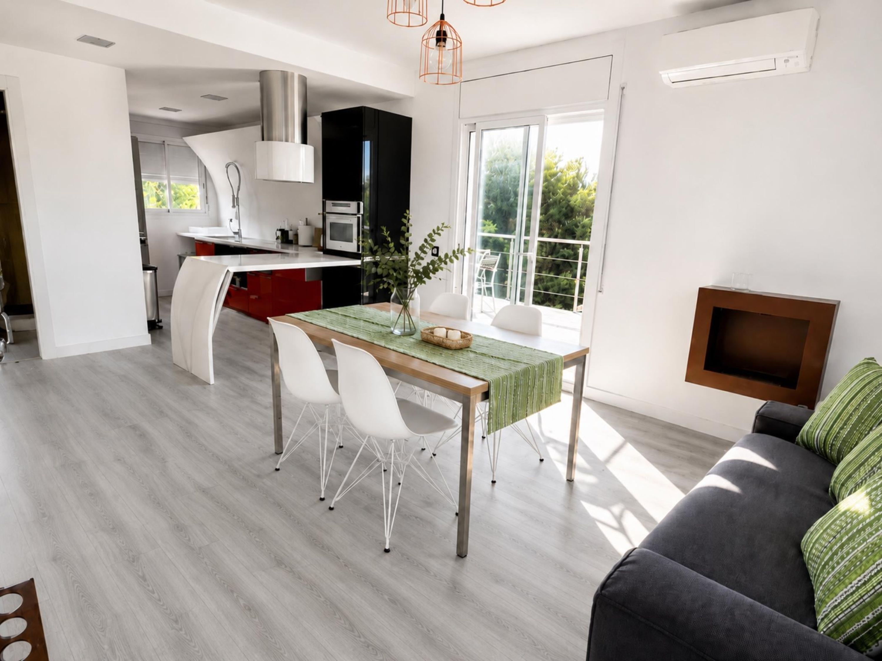 A modern kitchen with a dining area, a sofa, and a TV.