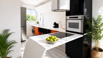 A modern kitchen with a central island, stainless steel appliances, and potted plants.