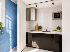 A modern kitchen with a stainless steel microwave, a sink, and a wooden cutting board.