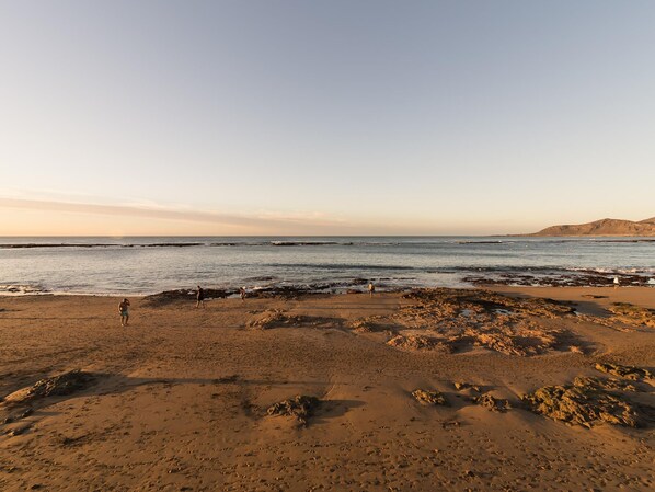 Uma praia com terreno rochoso e céu claro.