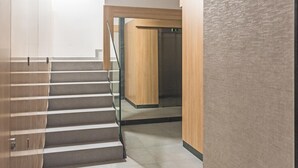 Un escalier moderne avec des rampes en verre menant à un ascenseur.