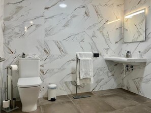 Un baño con inodoro, lavamanos y espejo.