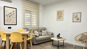 Una sala de estar moderna con un sofá, una mesa de comedor con sillas y una mesita auxiliar.