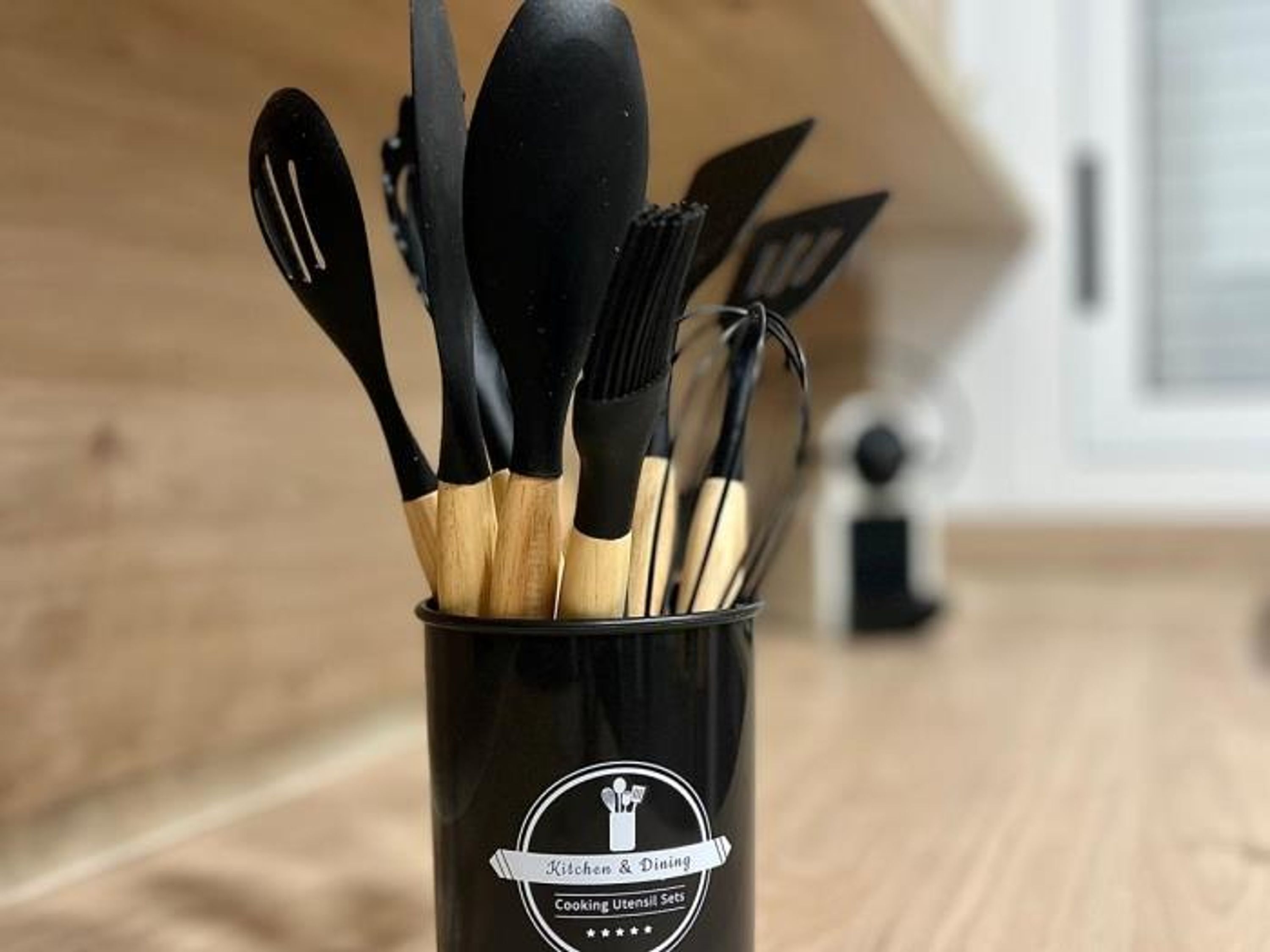 Un recipiente negro para utensilios de cocina con un logotipo y texto identificatorio.