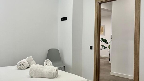 Una habitación de hotel con una cama, una silla y una puerta de madera que da a otra habitación.