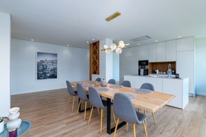 A modern dining area with a wooden table, grey chairs, and a hanging light fixture.
