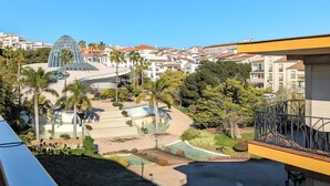 A residential area with a modern building featuring a glass dome, surrounded by palm trees and a swimming pool. - Apartamento Orquidario (Estepona)