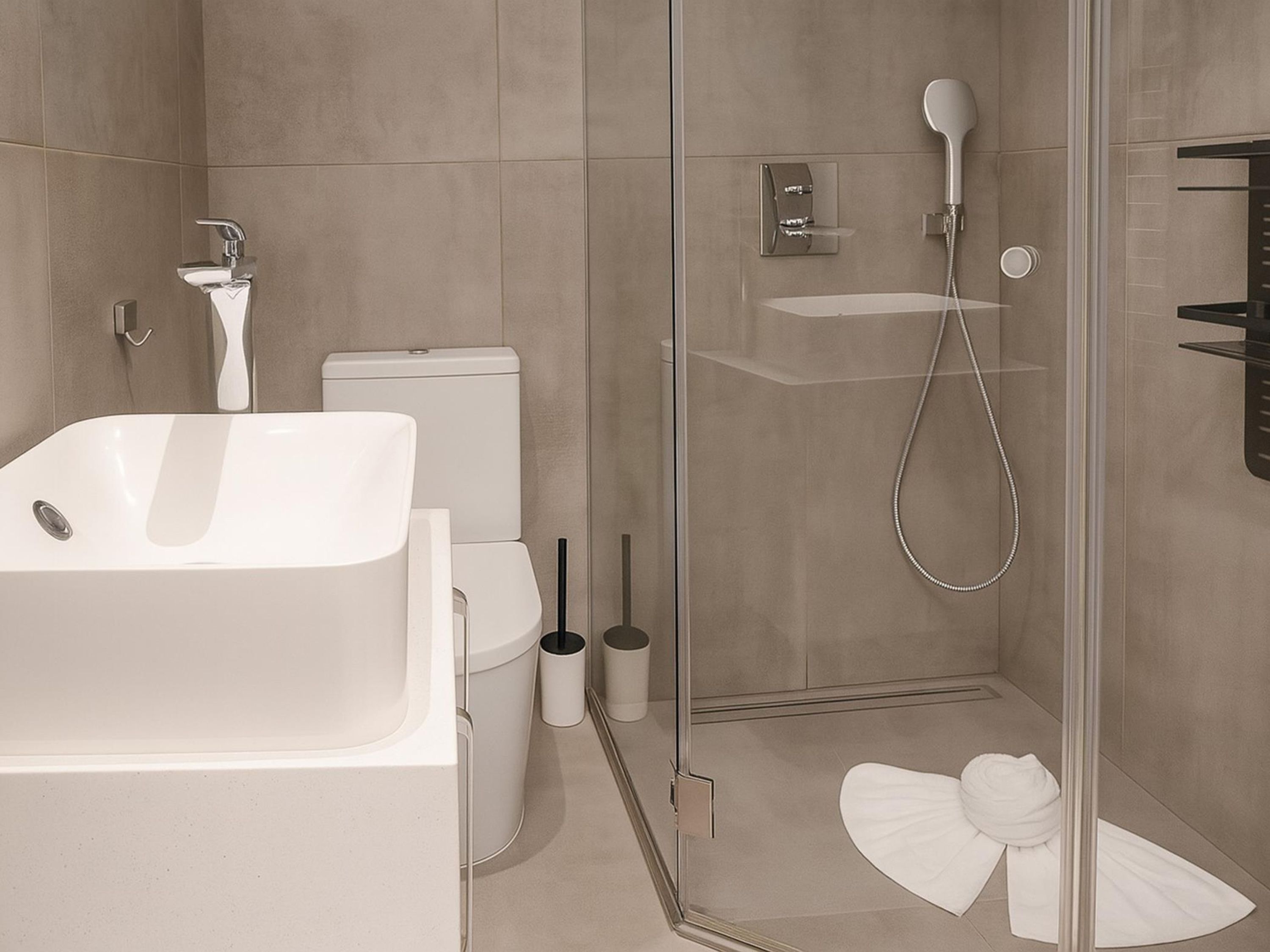 A modern bathroom with a glass-enclosed shower, a white sink, and a toilet.