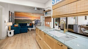 Una cucina moderna con una grande isola, forno integrato e un'ampia finestra vista tramonto.