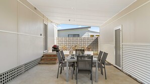 Un patio techado con mesa y sillas, una parrilla y una cerca decorativa.