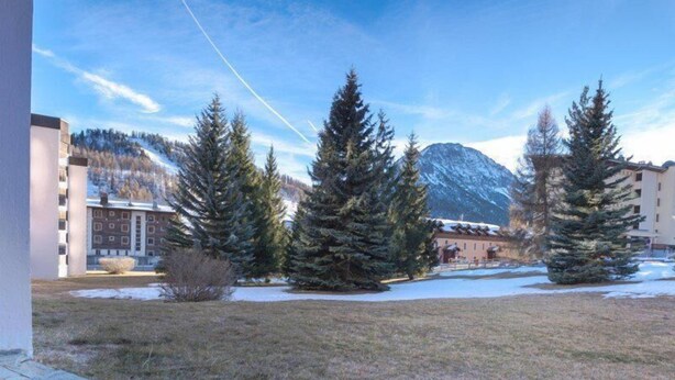 A courtyard with snow-covered ground, evergreen trees, and buildings in the background. - 50m from ski slopes, Ground floor, view mountain, parking, tv, ski locker, 18m², Montgenèvre (Montgenèvre)