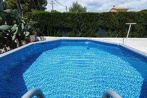 Piscina com superfície de água azul cristalina, rodeada por um deck branco e um sebedo.