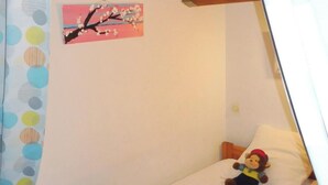 A single bed with a gray blanket, a small pillow, and a stuffed toy. A painting of a tree with pink blossoms hangs on the wall. - 50 m from the beach (Agde)