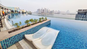Ein Pool ohne Ende mit Blick auf die Stadt, ein Liegebereich inklusive Wasserrutsche und eine Poolbar.
