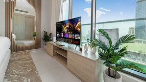 Ein modernes Wohnzimmer mit großem Flachbildfernseher, einer Couch, einem Couchtisch und einer Topfpflanze.