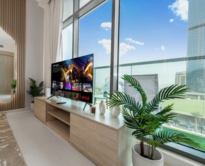 Un salon moderne avec un grand téléviseur à écran plat, un canapé, une table basse et une plante en pot.