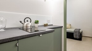 Una cocina moderna con un hervidor, un tazón y una planta en maceta sobre la encimera.