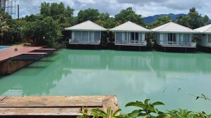 A row of overwater bungalows with a pool in the foreground. - The wide view resort cafe (Thep Krasattri)