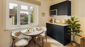 Eine Küche mit Essbereich, einer schwarzen Mikrowelle und einem Blumentopf.