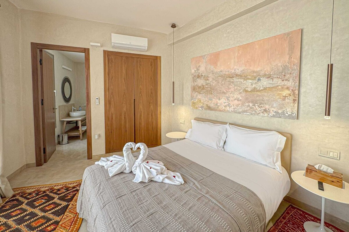A hotel room with a bed, a bedside table, a mirror, a wardrobe, and a painting on the wall.
