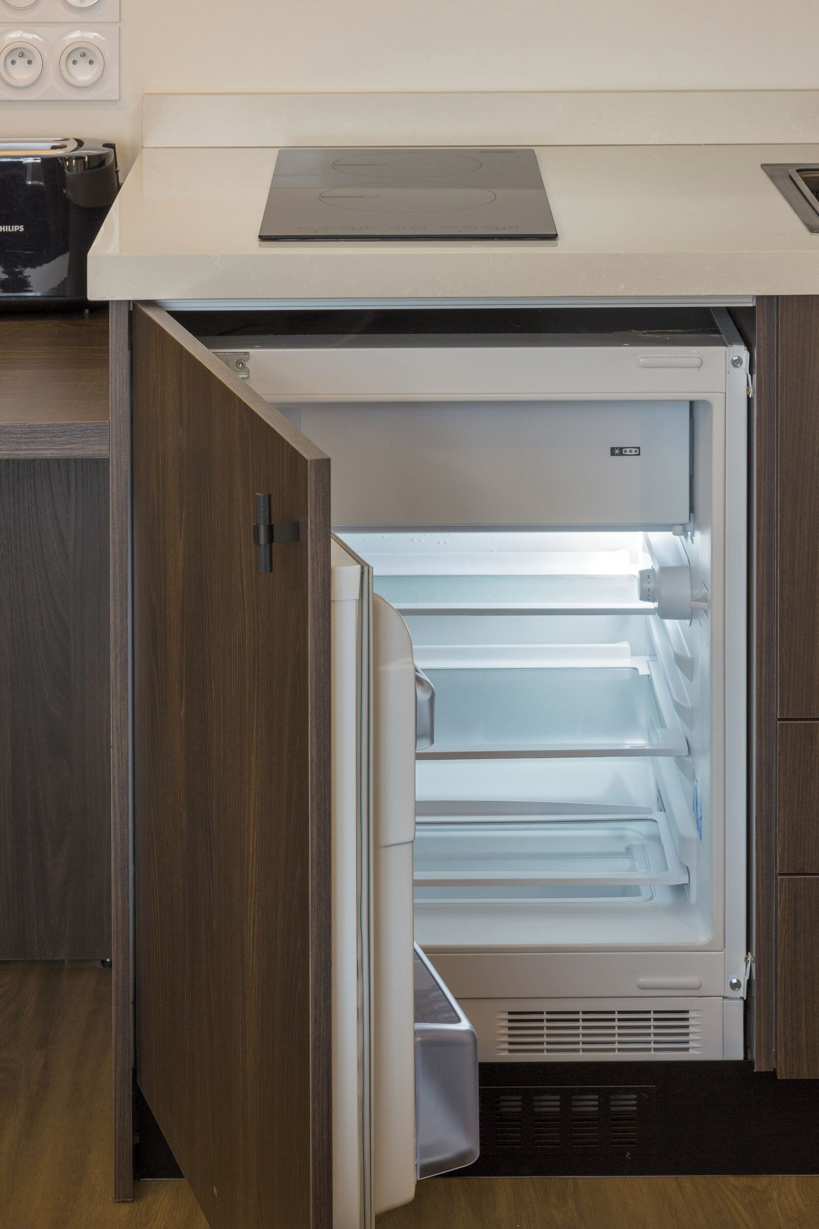 A compact refrigerator with a transparent door, a control panel, and a built-in ice maker.