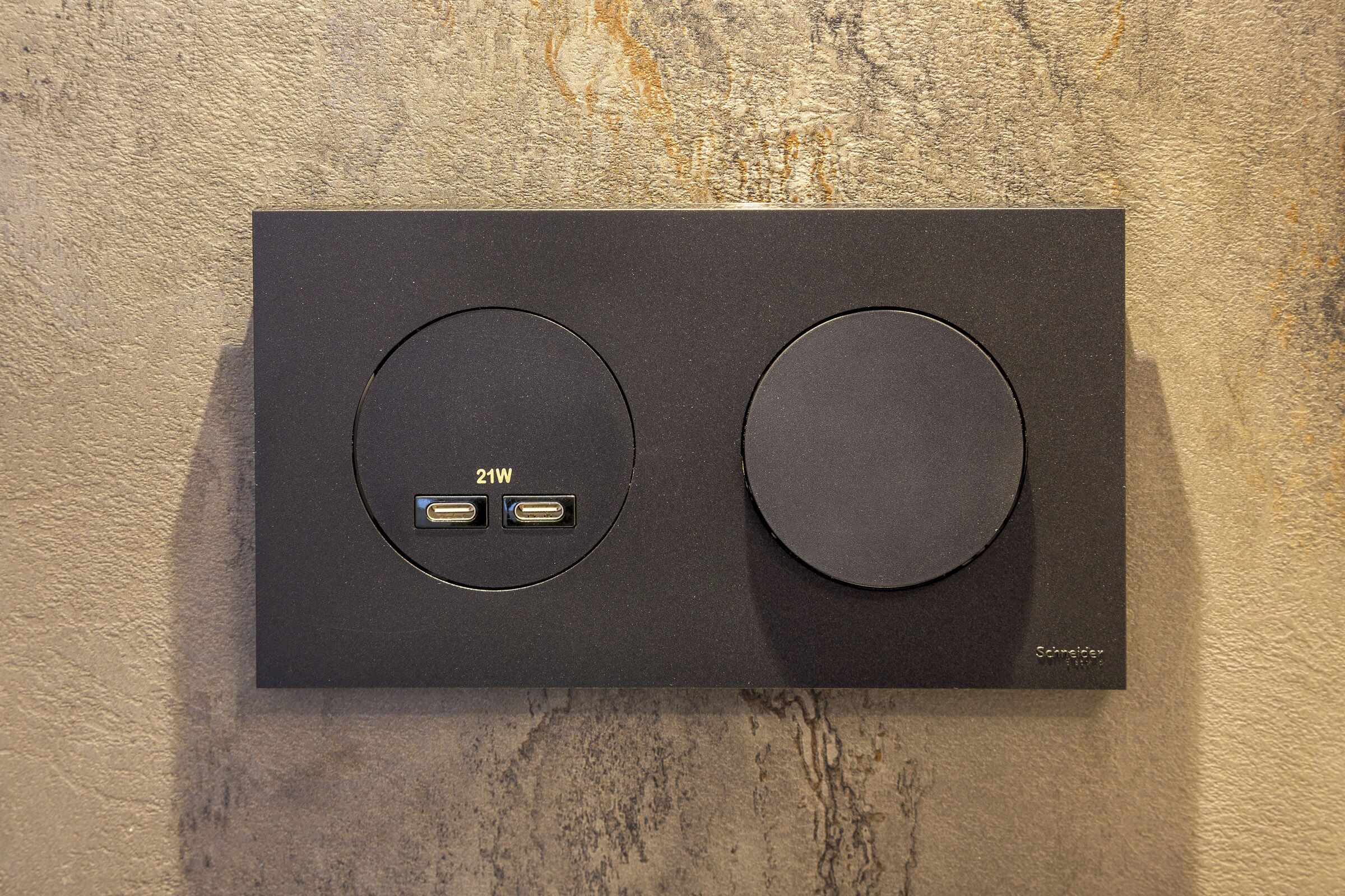 Painel de controle preto com dois botões circulares e duas portas USB rotuladas '21W'.