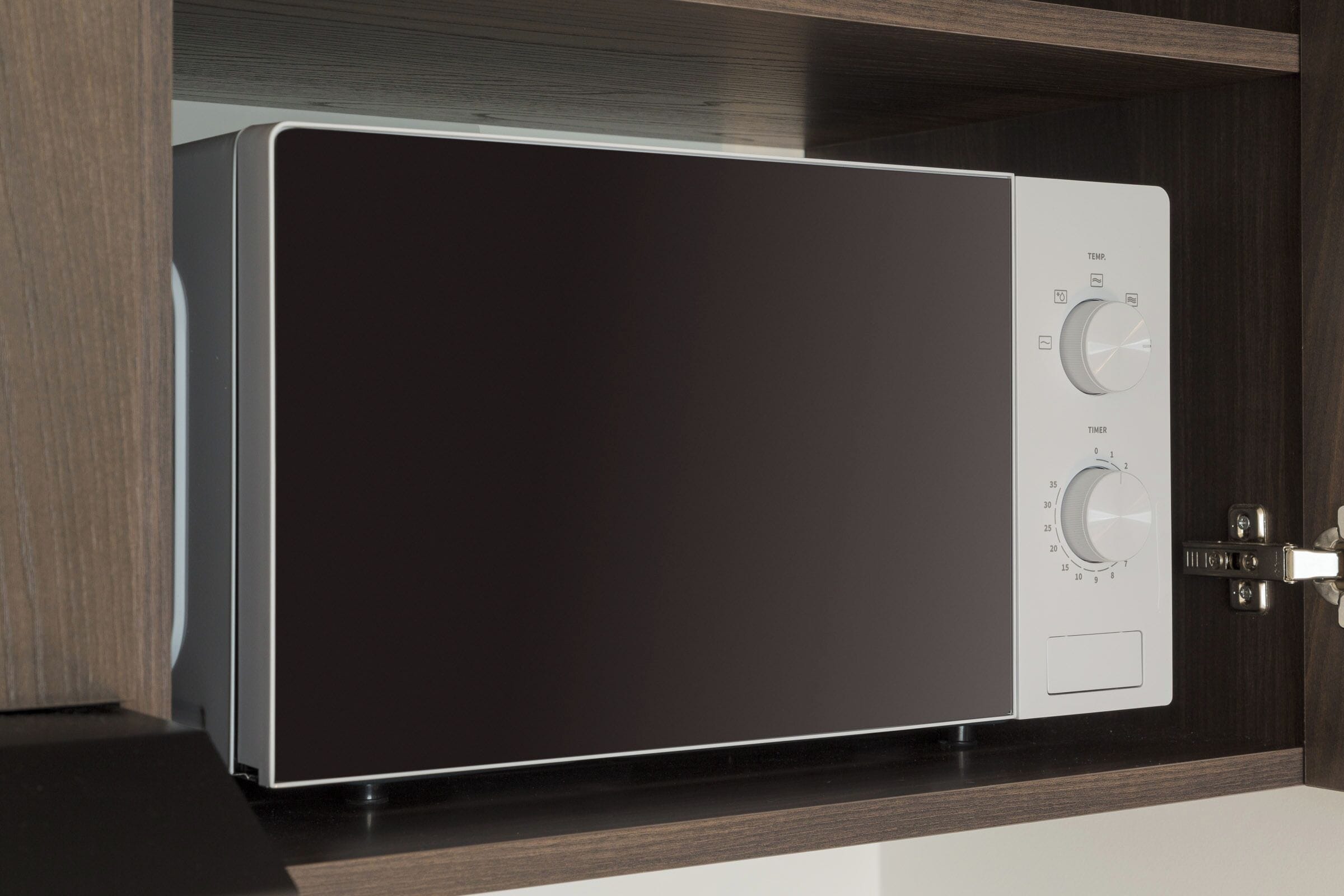 A modern, built-in washer and dryer unit with two control knobs and a metal latch.