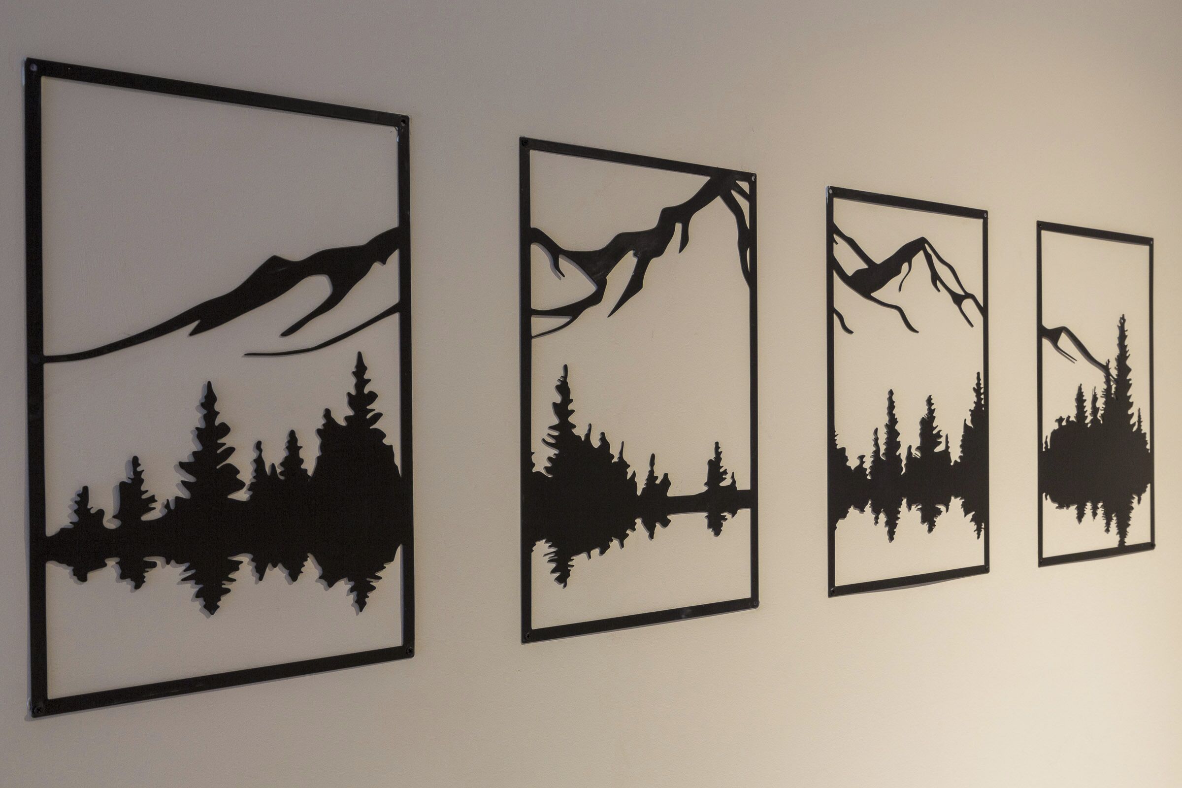 Four framed silhouettes of mountain landscapes with trees.