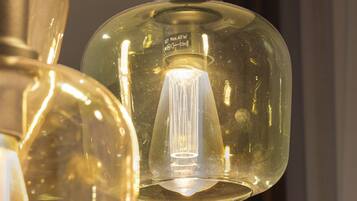 A close-up of a pendant light fixture with a clear glass shade and a visible filament bulb.