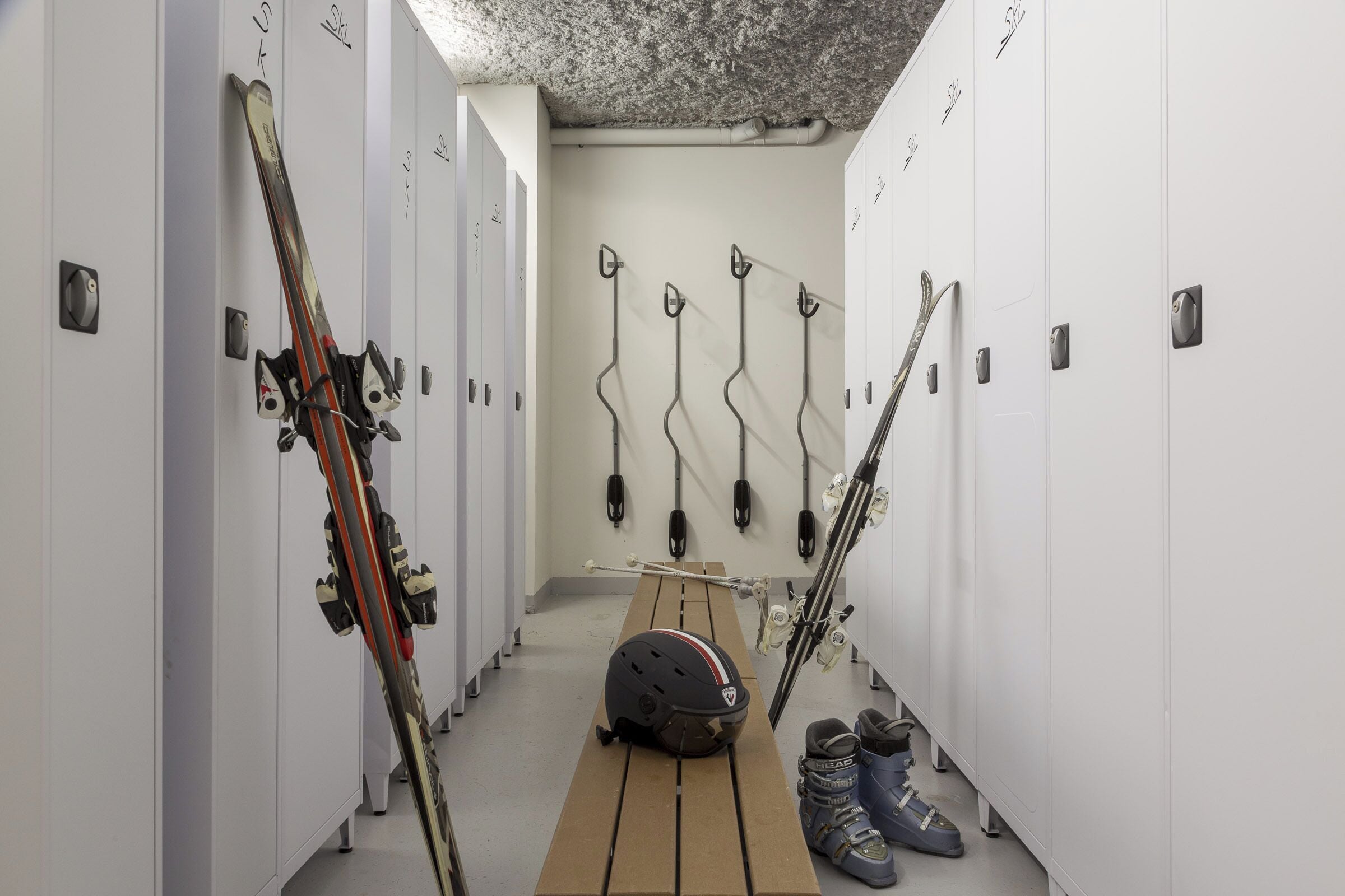 Un vestiaire équipé de plusieurs casiers, de paires de skis et de bâtons de ski.