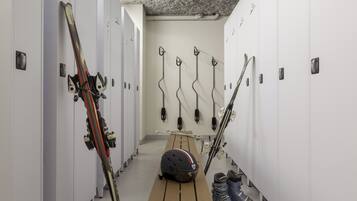 Un vestiaire équipé de plusieurs casiers, de paires de skis et de bâtons de ski.