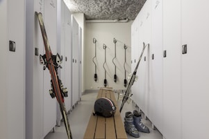 A locker room with multiple lockers, skis, and ski poles.