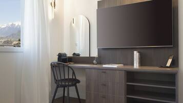 Une chambre moderne dotée d’une grande fenêtre, d’un bureau avec une chaise, d’un téléviseur à écran plat et d’une bibliothèque.