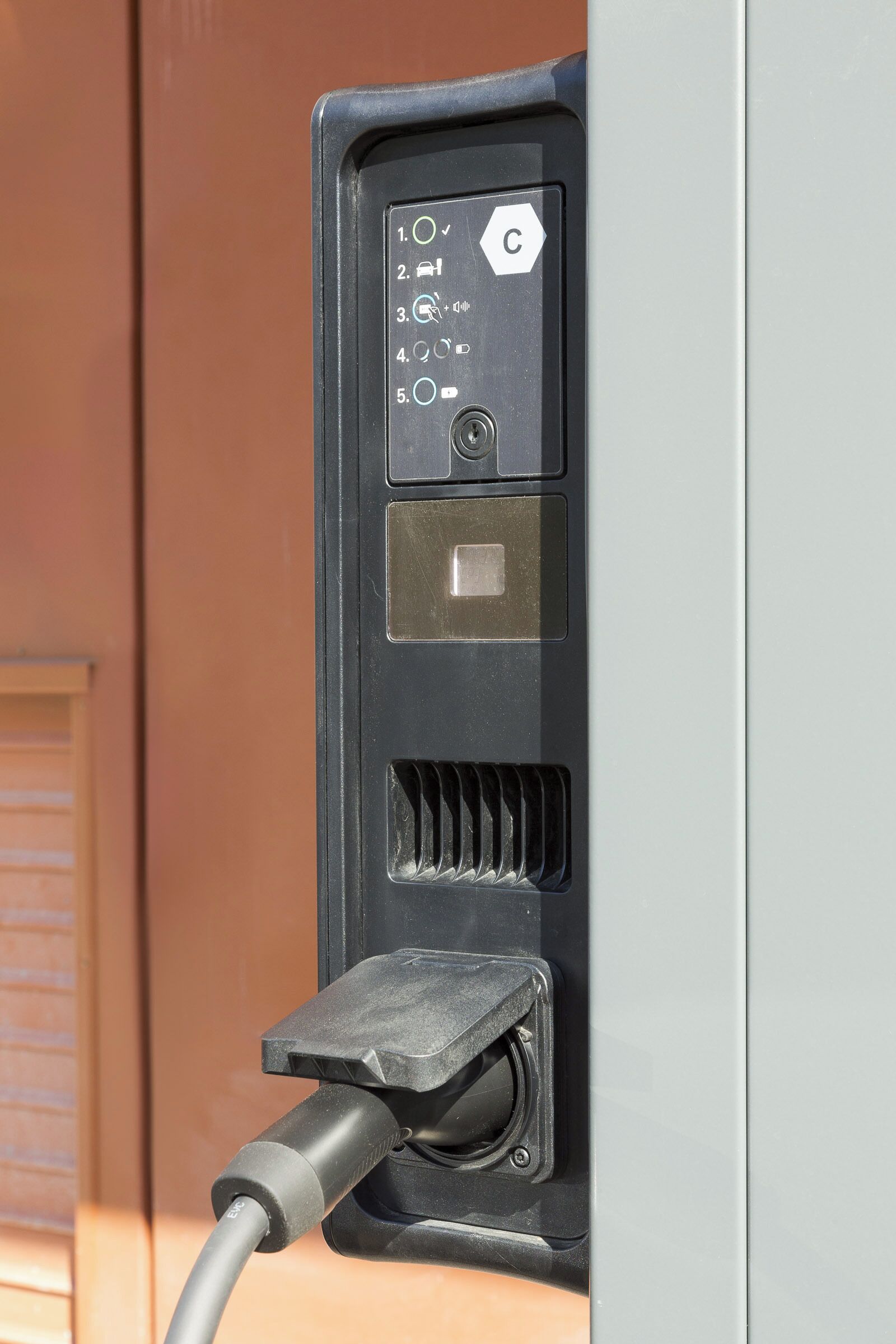 A black electrical outlet with a plug inserted, a lock, and a keyhole.