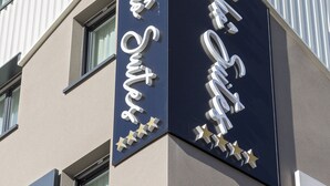A hotel sign with the name 'Nelle Suite' and a modern building facade.