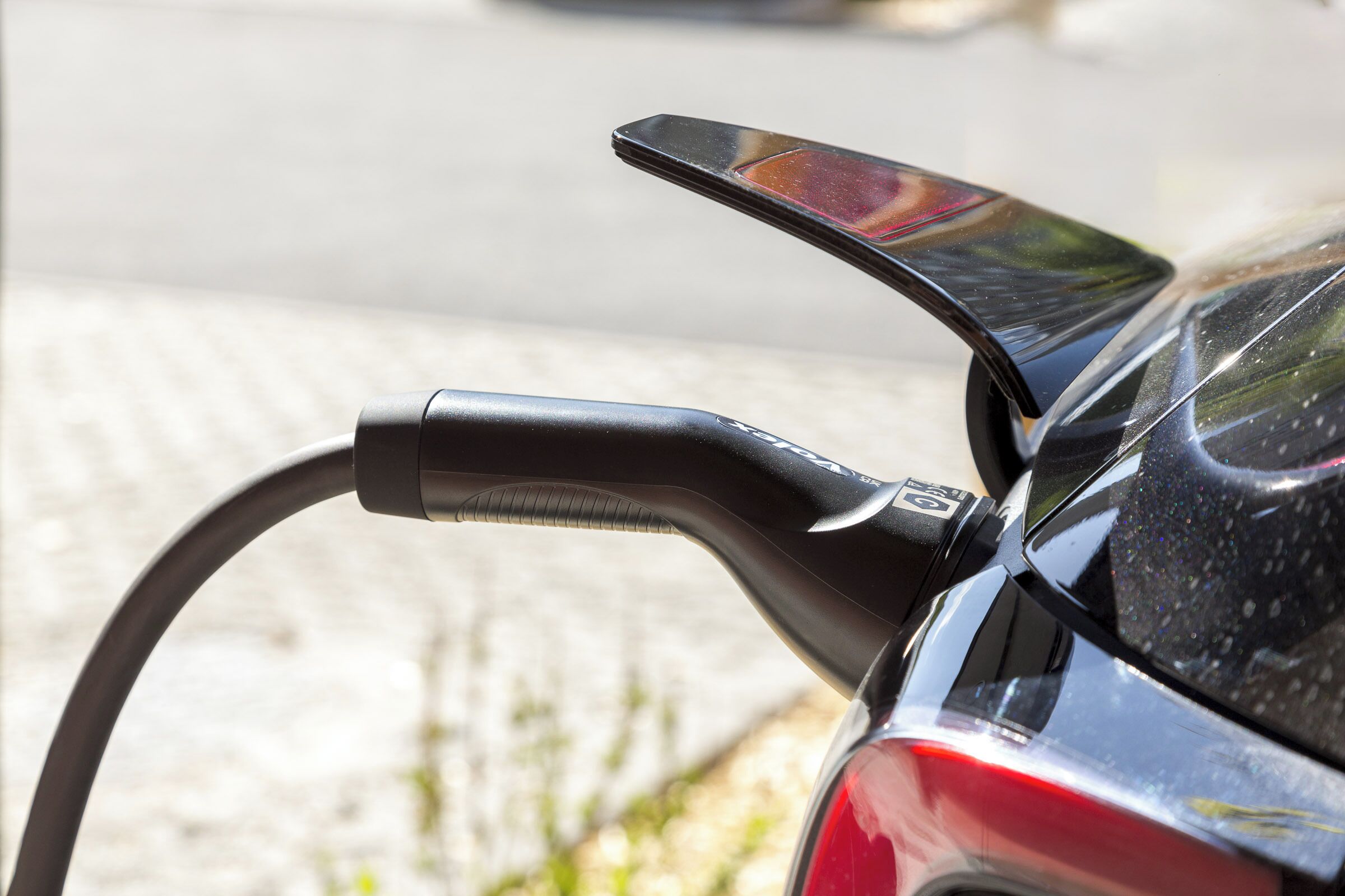 A car with a charging cable connected to its rear.