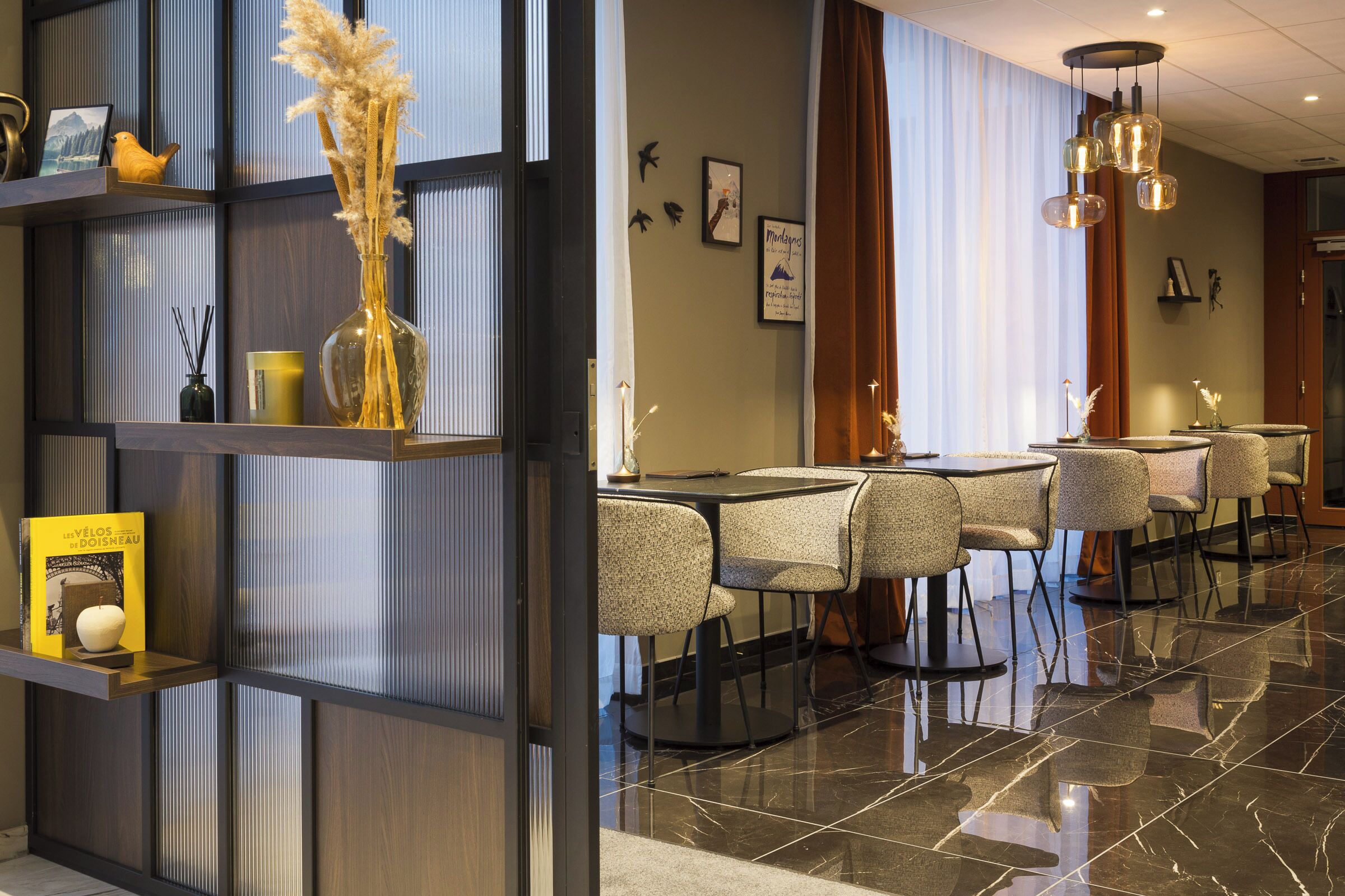 Un vestíbulo de hotel con mostrador de recepción, zona de estar y una pared decorativa con un libro y un jarrón.
